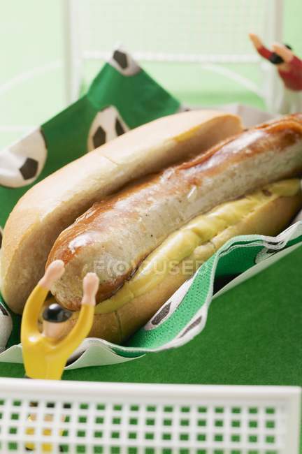 Hot dog with mustard and toy footballers — Stock Photo
