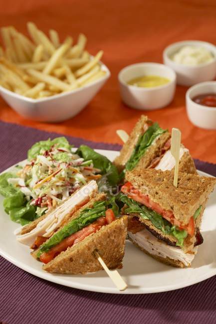 Sandwich Club Turquie avec salade de chou et frites sur surface rouge — Photo de stock