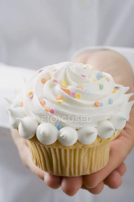 Mãos femininas segurando cupcake na placa — Fotografia de Stock