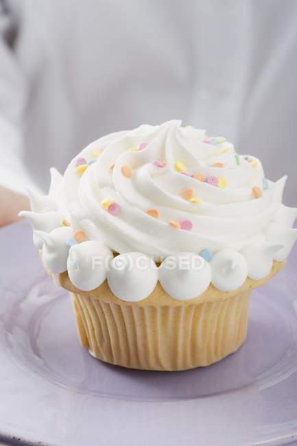 Manos femeninas sosteniendo cupcake en el plato - foto de stock