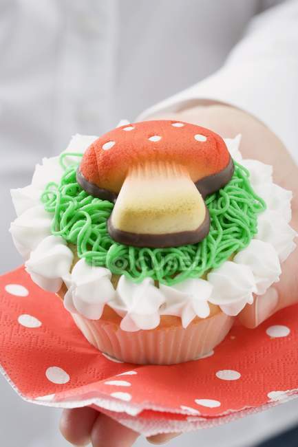Manos celebración cupcake con mazapán volar agárico - foto de stock