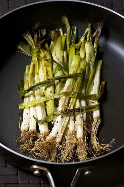 Жареный весенний лук в сковороде — стоковое фото