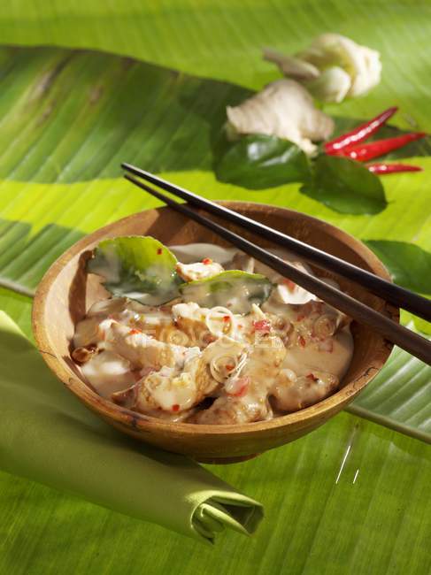 Closeup view of spicy turkey in coconut sauce with chopsticks on leaves — Stock Photo