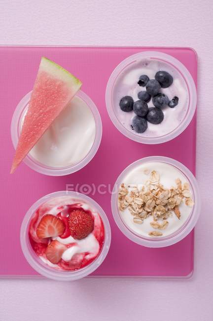 Vier Joghurts mit Beeren und Müsli — Stockfoto