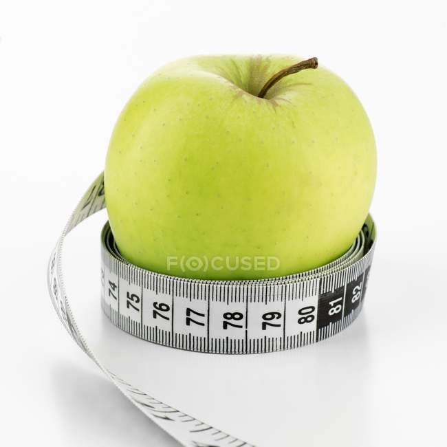 Manzana verde con cinta métrica - foto de stock