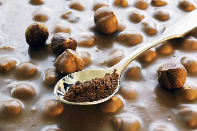 Nussschokolade und ein Teelöffel Kakaopulver — Stockfoto