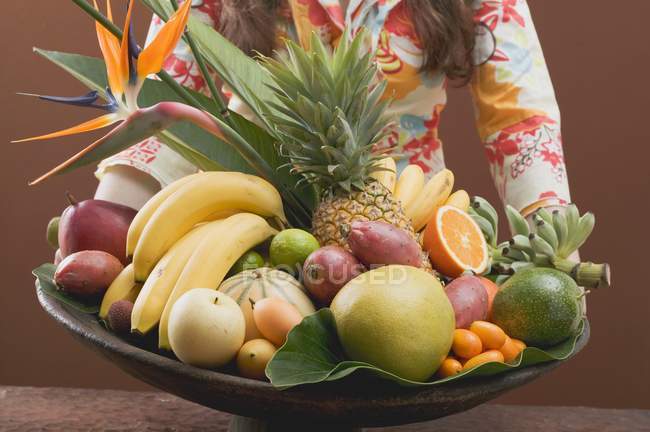 Frau hält Schale mit exotischen Früchten — Stockfoto