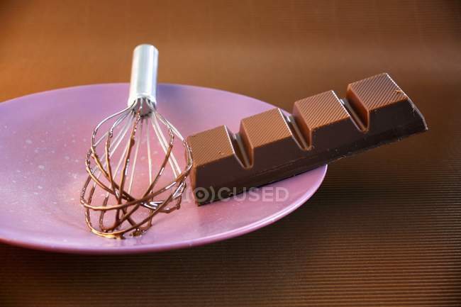 Pezzo di cioccolato su piatto viola — Foto stock