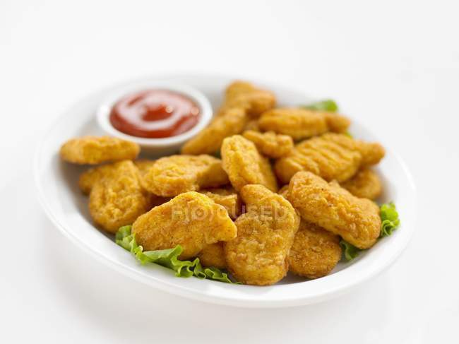 Vista de cerca de nuggets de pollo en hojas de ensalada con salsa - foto de stock