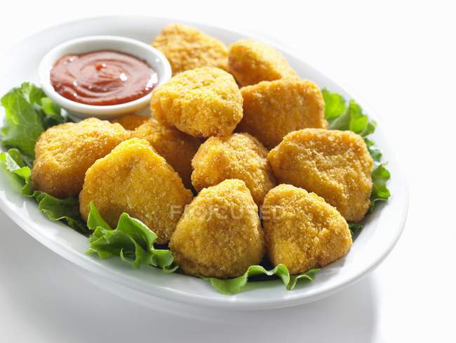 Vista de cerca de nuggets de pollo con salsa en la hoja de ensalada - foto de stock