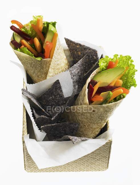 Envolturas vegetales y chips de tortilla sobre fondo blanco - foto de stock