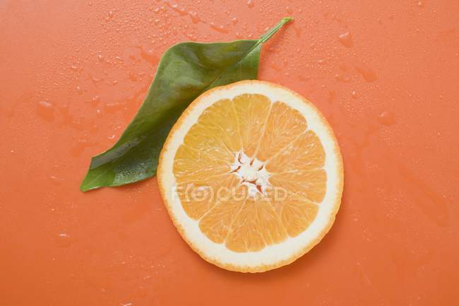 Rebanada de naranja con hoja - foto de stock