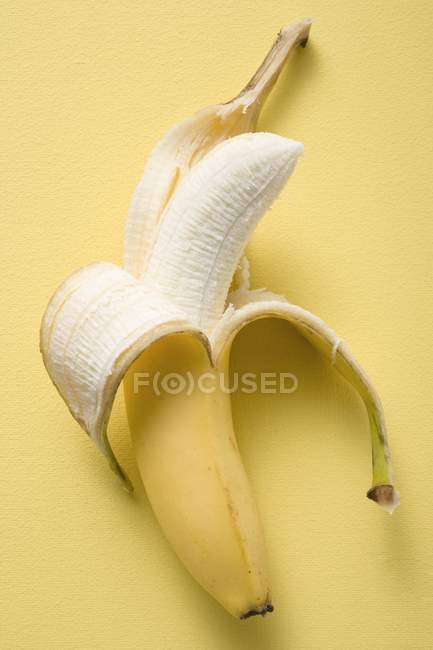 Полуочищенный спелый банан — стоковое фото