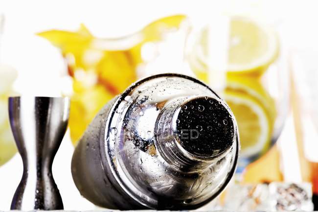 Closeup view of wet cocktail shaker with fruit on background — Stock Photo