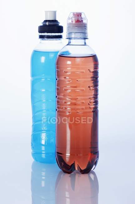 Vista de cerca de las bebidas rojas y azules en botellas de plástico - foto de stock