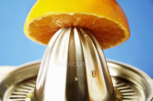 Naranja en exprimidor de cítricos - foto de stock