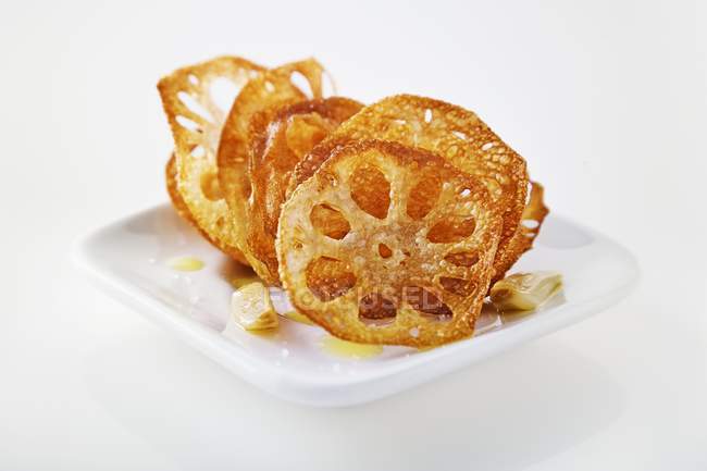 Radice di loto fritto con aglio e olio d'oliva su sfondo bianco — Foto stock