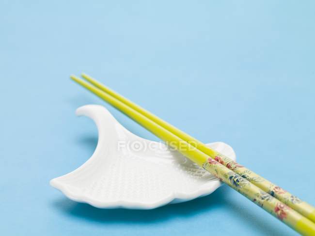 Closeup view of white dish and chopsticks on blue surface — Stock Photo