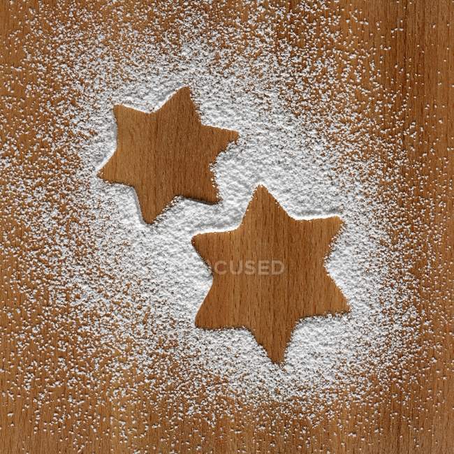 Top view of star shapes in icing sugar on wooden surface — Stock Photo
