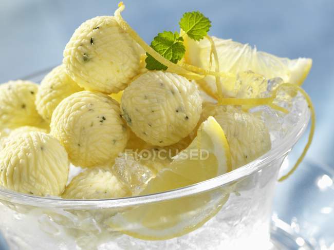 Vista de cerca de bolas de mantequilla de limón con cuña de limón y cáscara sobre hielo - foto de stock