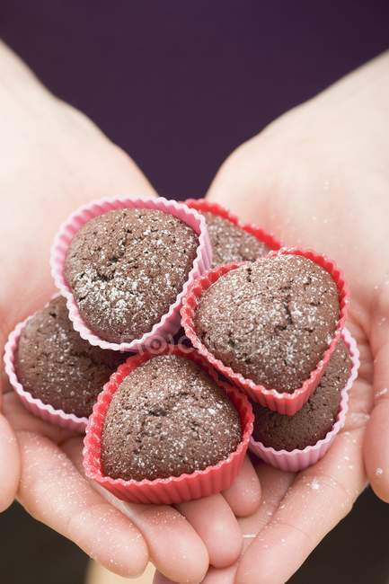 Closeup cropped view of hands holding heart-shaped chocolate buns — Stock Photo