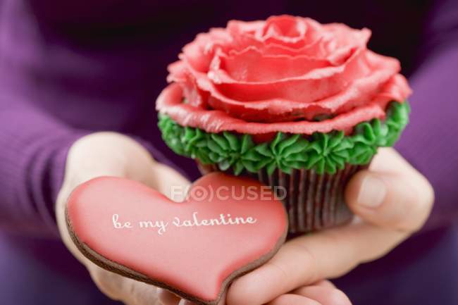 Hands holding cupcake and biscuit — Stock Photo