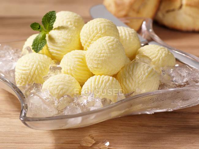 Vue rapprochée des boules de beurre sur glace avec des herbes — Photo de stock