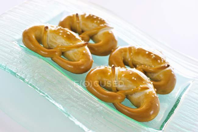 Fresh soft pretzels on a glass plate — Stock Photo
