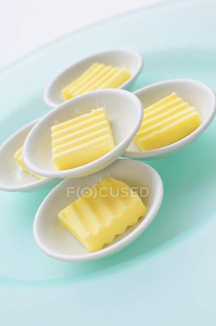 Nahaufnahme gekippte Ansicht von Butterstücken in weiß gestapelten Tellern — Stockfoto