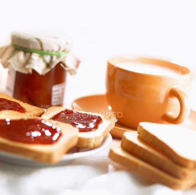 Vista de primer plano de tostadas con mermelada y taza de leche - foto de stock