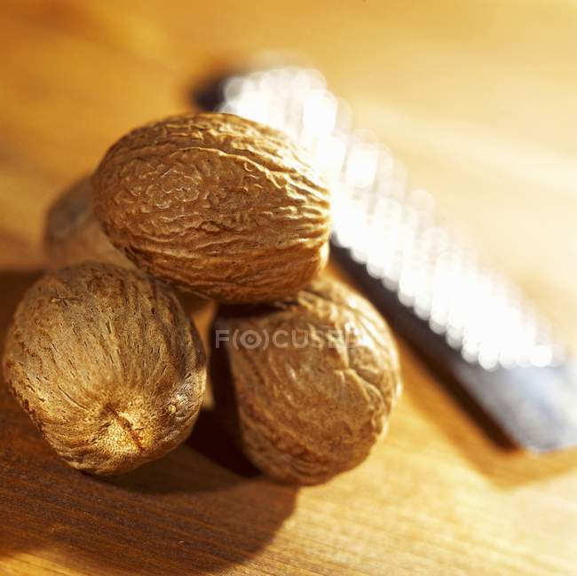 Nutmegs enteros con rallador - foto de stock