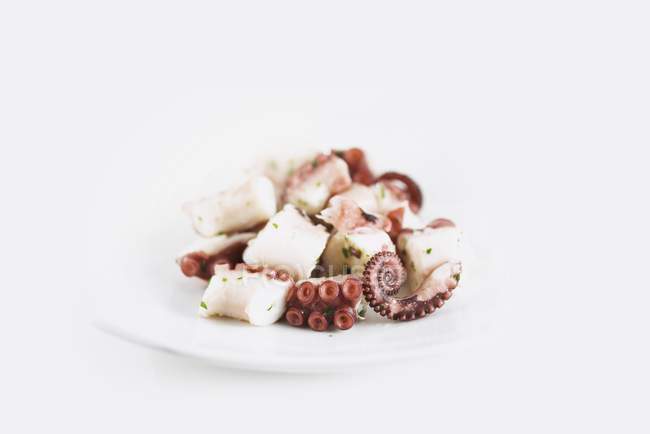 Closeup view of marinated octopus pieces on white plate — Stock Photo