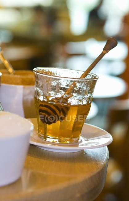 Glass on plate of honey — Stock Photo