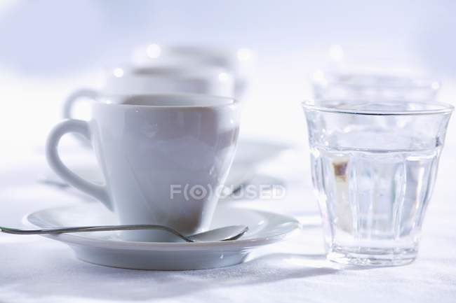 Крупный план трех чашек эспрессо со стаканами воды — стоковое фото