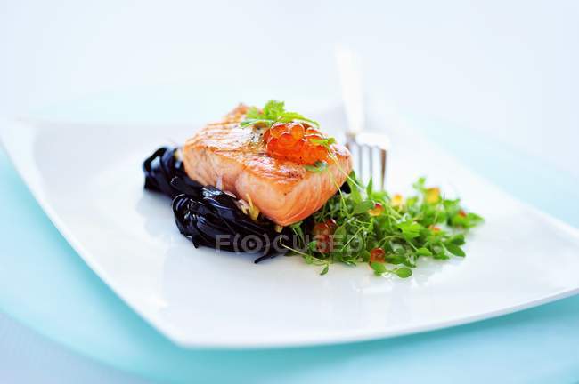 Жареный лосось на чёрной тальятелле — стоковое фото