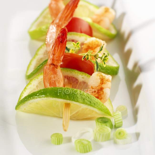Prawn, lime and tomato skewer on white plate — Stock Photo