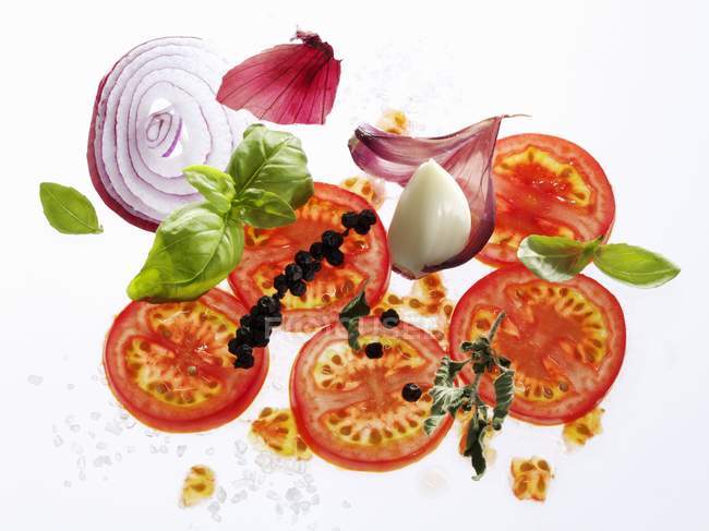 Tomates, hierbas, pimienta, ajo y cebolla sobre fondo blanco - foto de stock