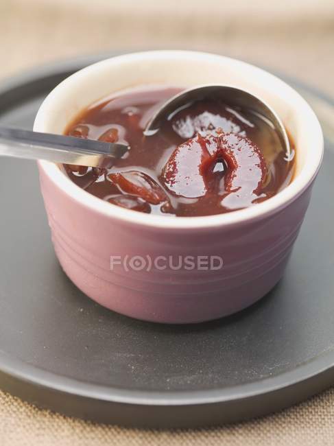 Closeup view of spiced plum sauce in dish with ladle — Stock Photo