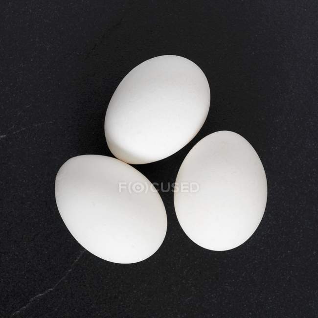 Білі яйця на чорному — стокове фото