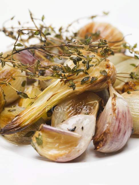 Roasted garlic with thyme on white surface — Stock Photo