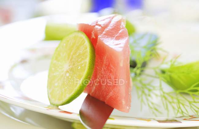 Vista close-up de atum cru com limão em faca e prato — Fotografia de Stock