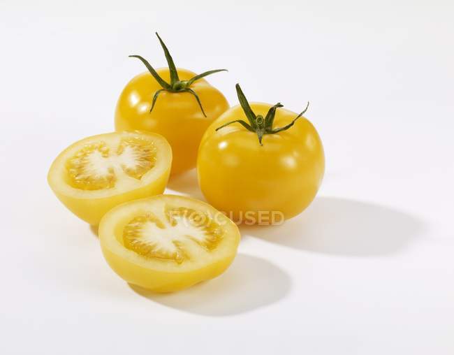 Tomates jaunes entières et coupées en deux — Photo de stock