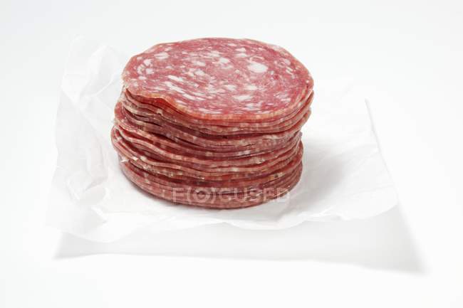 Vista close-up de fatias empilhadas de salsicha de porco mettwurst em papel branco — Fotografia de Stock