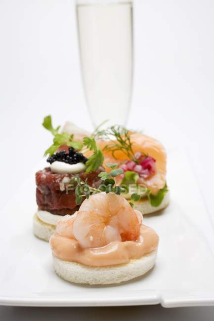 Assorted canapes and glass of sparkling wine — Stock Photo