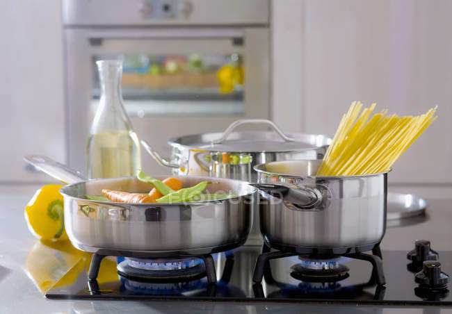 Hortalizas y espaguetis en sartenes - foto de stock