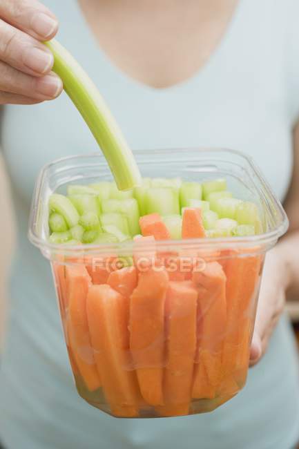 Donna che mangia sedano dal contenitore di plastica — Foto stock