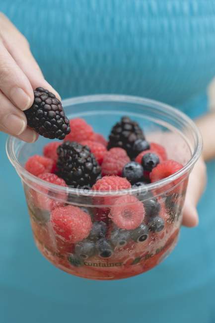 Woman holding plastic tub of berries — Stock Photo