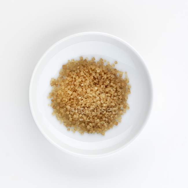 Вид зверху на коричневий тростинний цукор на білій тарілці — стокове фото