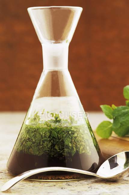 Closeup view of glass carafe of mint sauce and spoon — Stock Photo