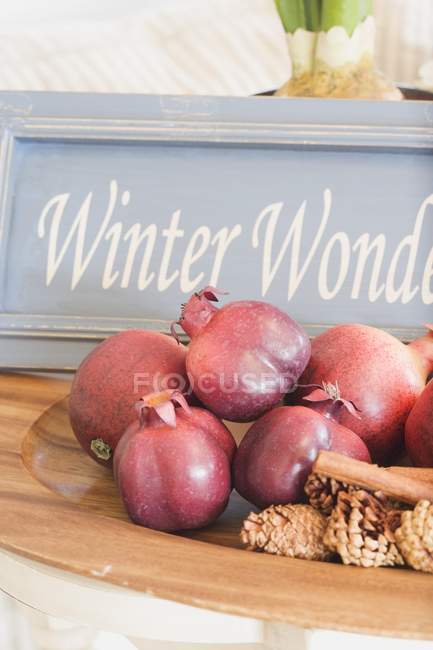 Closeup view of pomegranates with cones, cinnamon sticks and sign — Stock Photo
